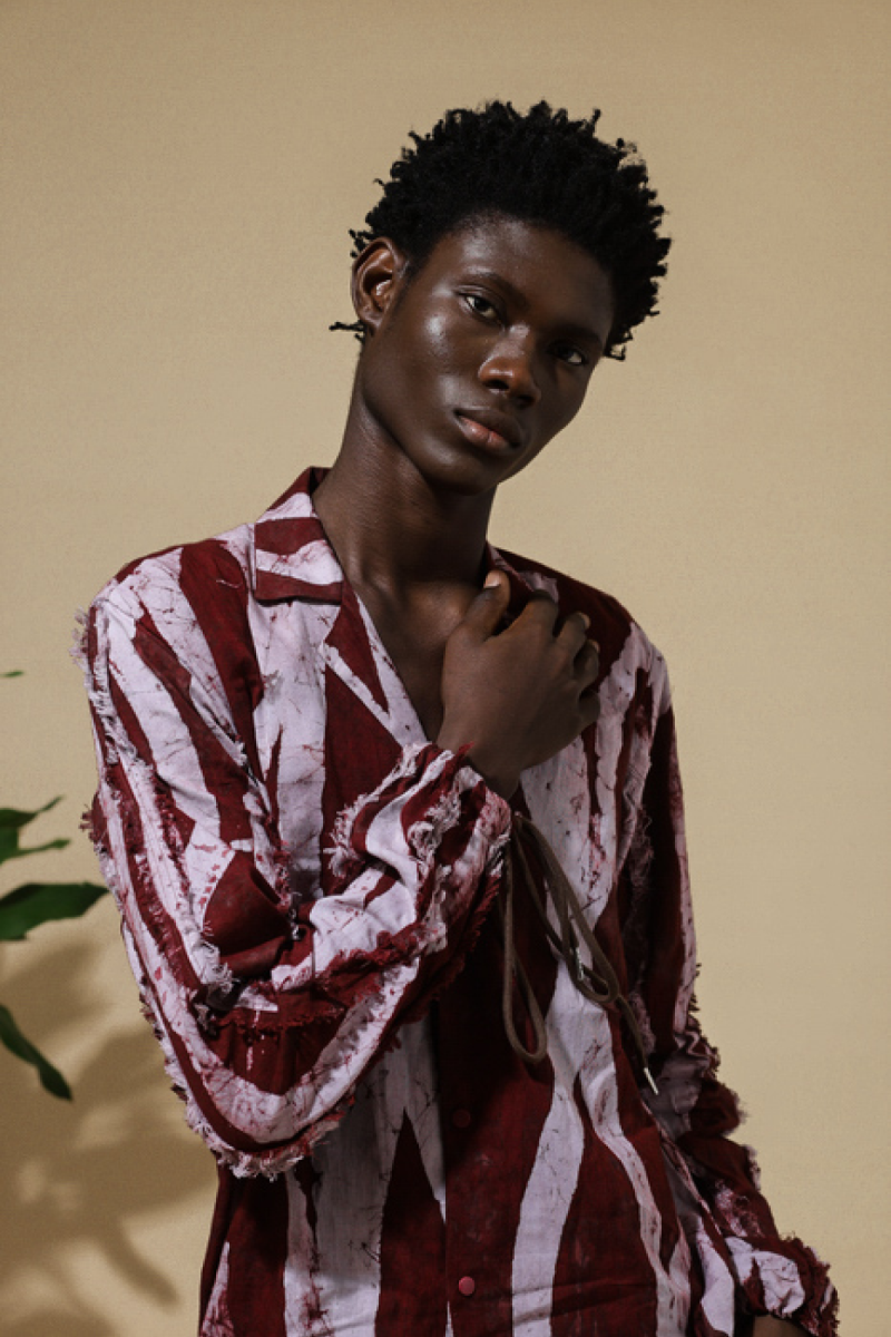 Portrait of male model in Cute Saint Irin-Ajo burgundy and white distressed stripe batik long-sleeve shirt with frayed edges and brown cord tie